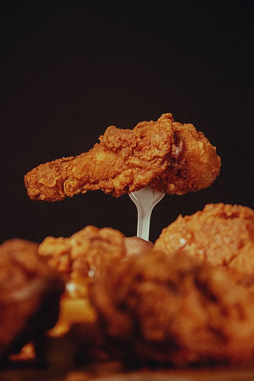 A fried chicken leg held on a fork.